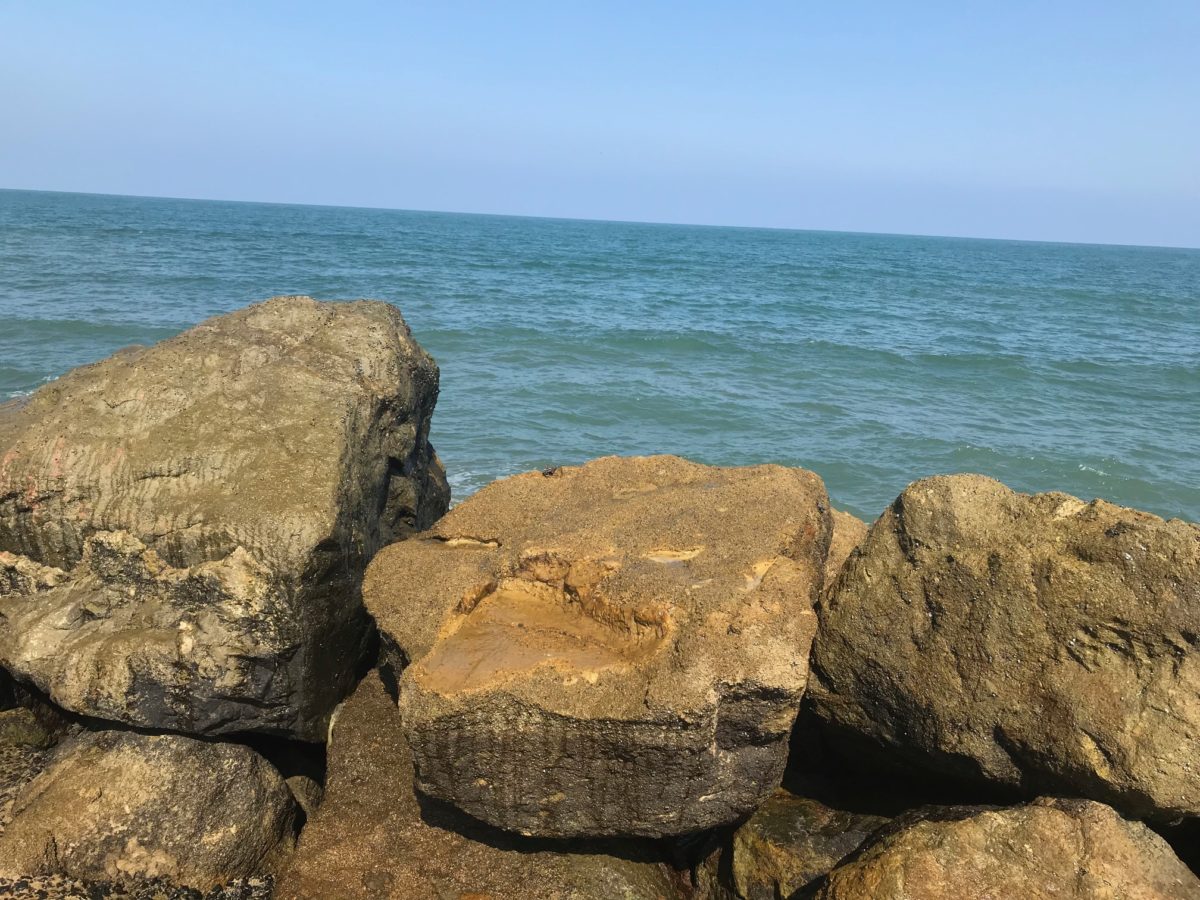 A wall of boulders with the sea in the background.