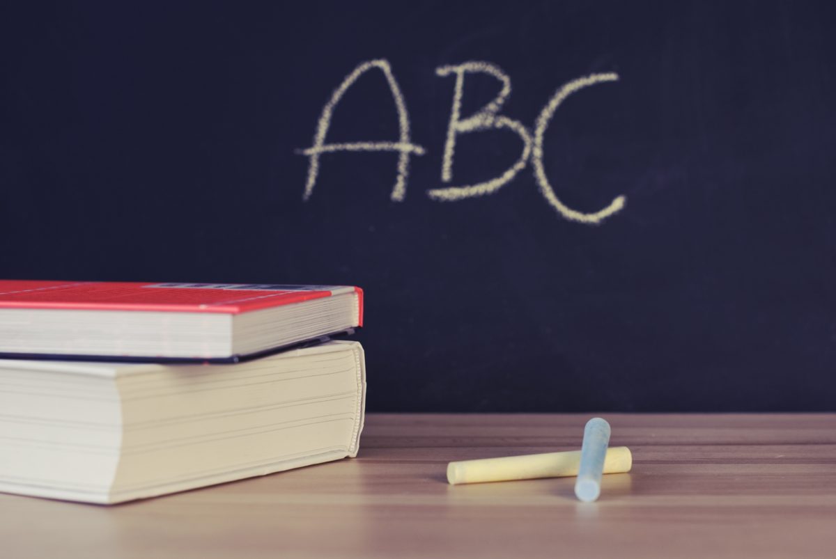 A blackboard with the letters "ABC" on it, and books and chalk on a desk.
