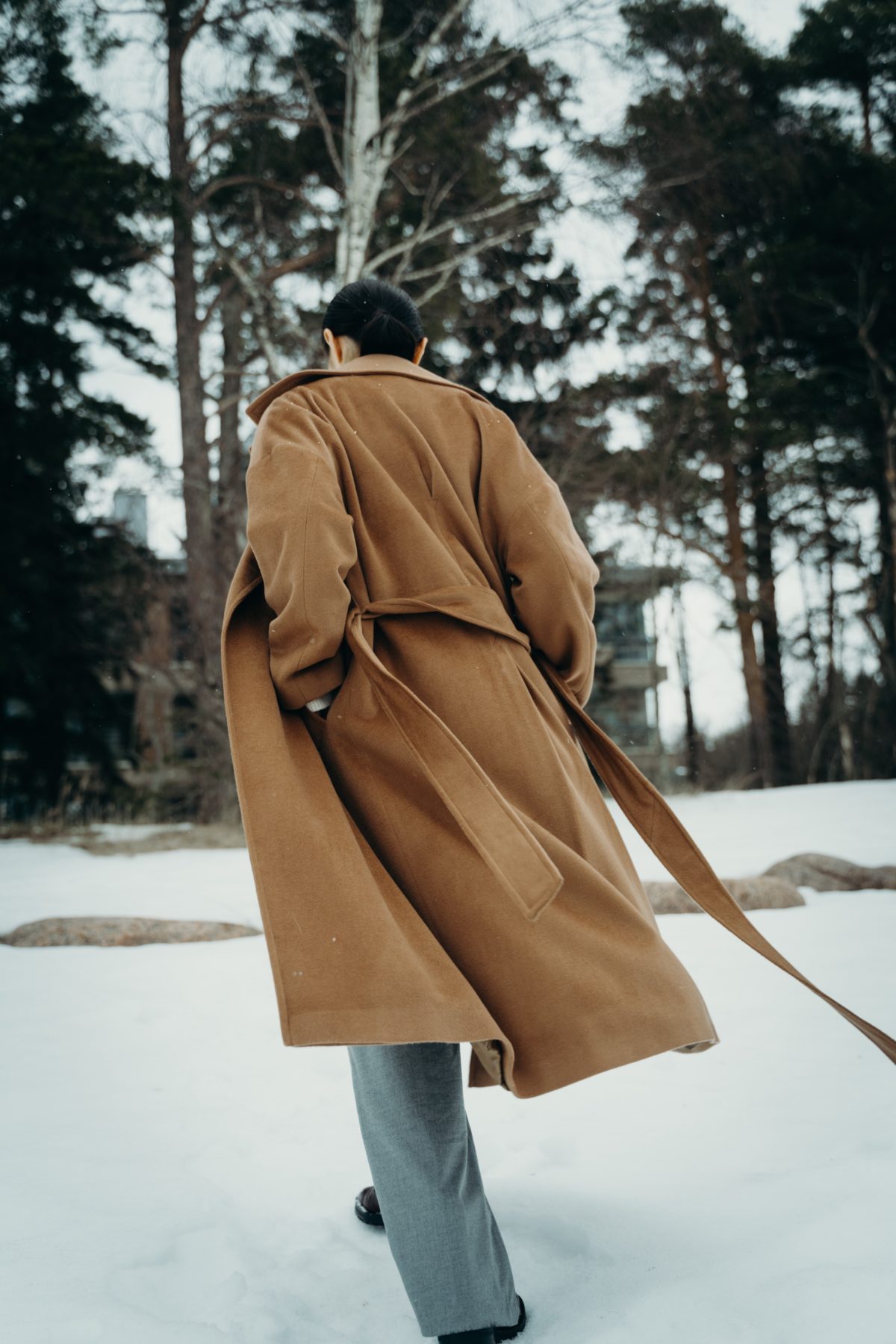 Person wearing a formal winter coat and walking away from the camera.