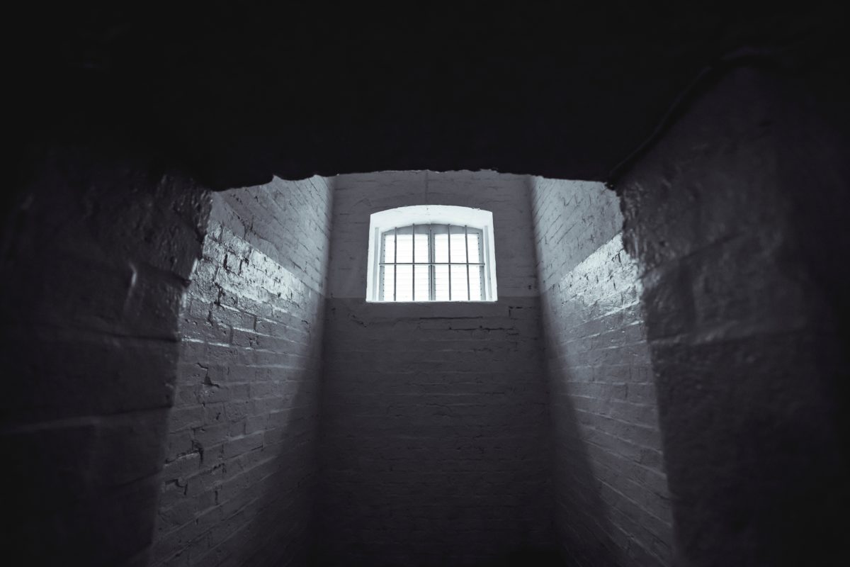 A prison cell with a single, high window.