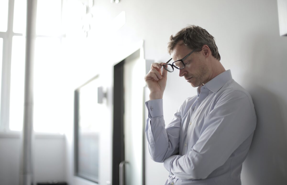 Man leaning against wall looking anxious.