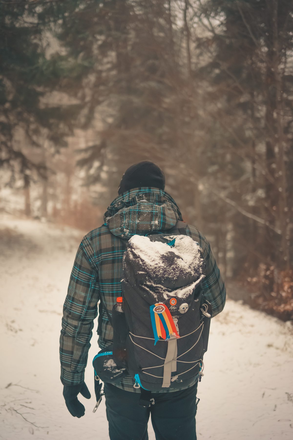 Person walking uphill in the snow with a backpack.