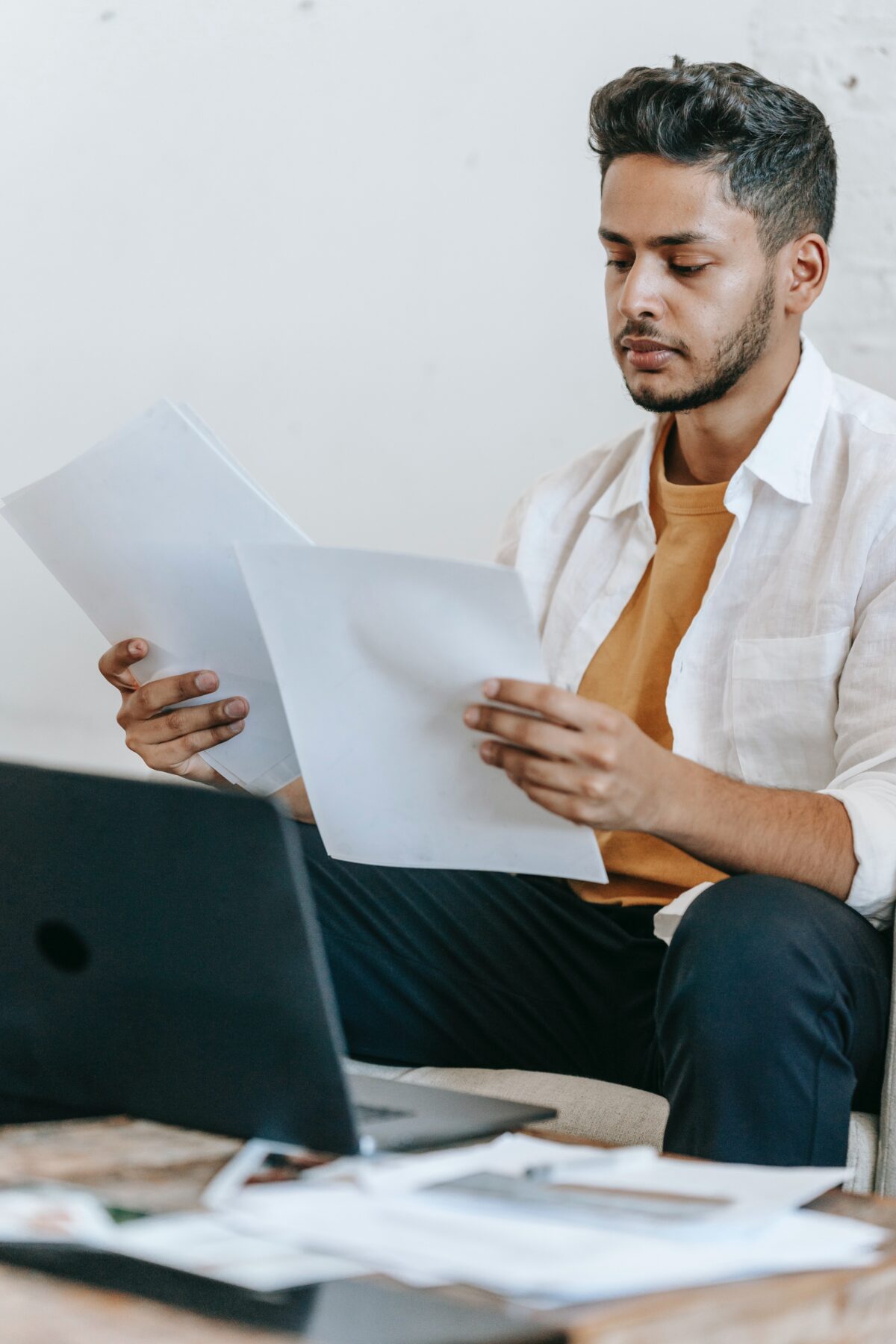 A young man reading pages at work.