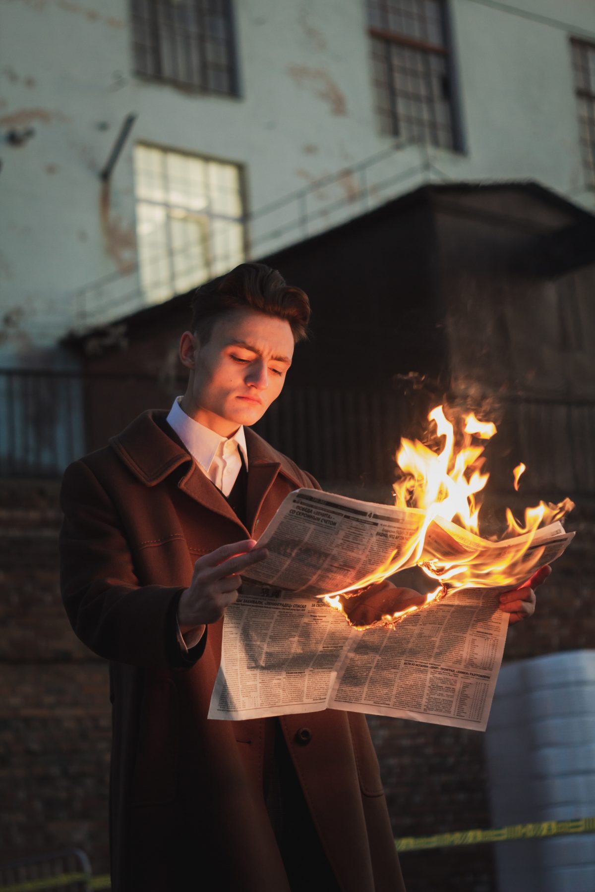 Man holding newspaper which is on fire.