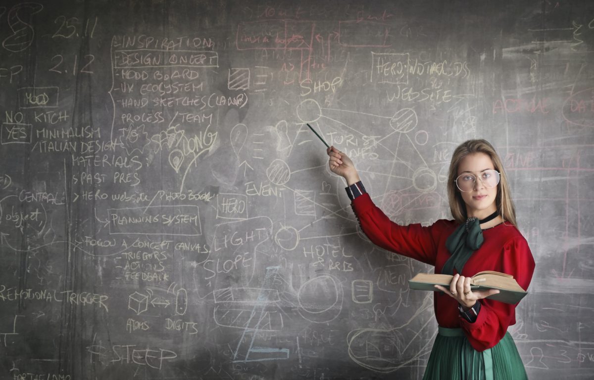 Female Professor with complicated scribbles on the blackboard.