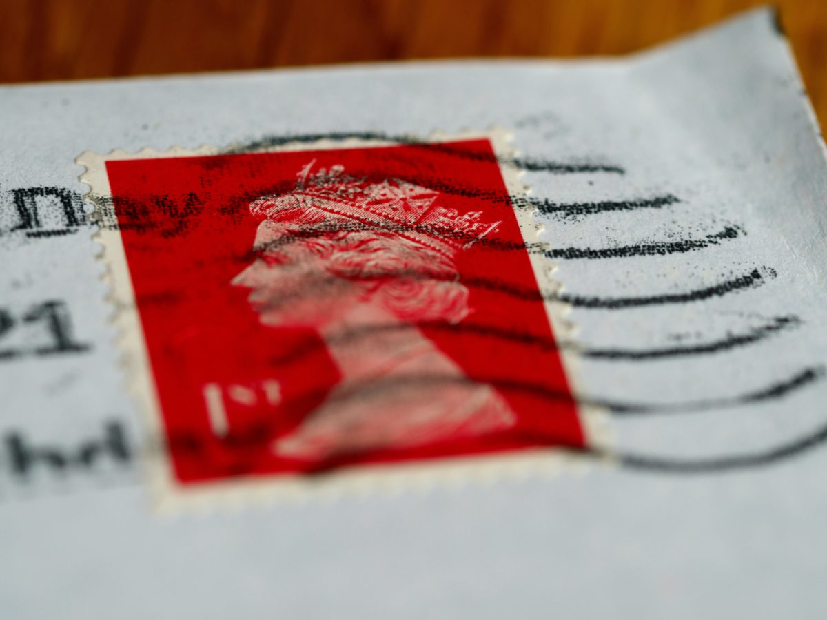A red postage stamp bearing the head of the Queen.