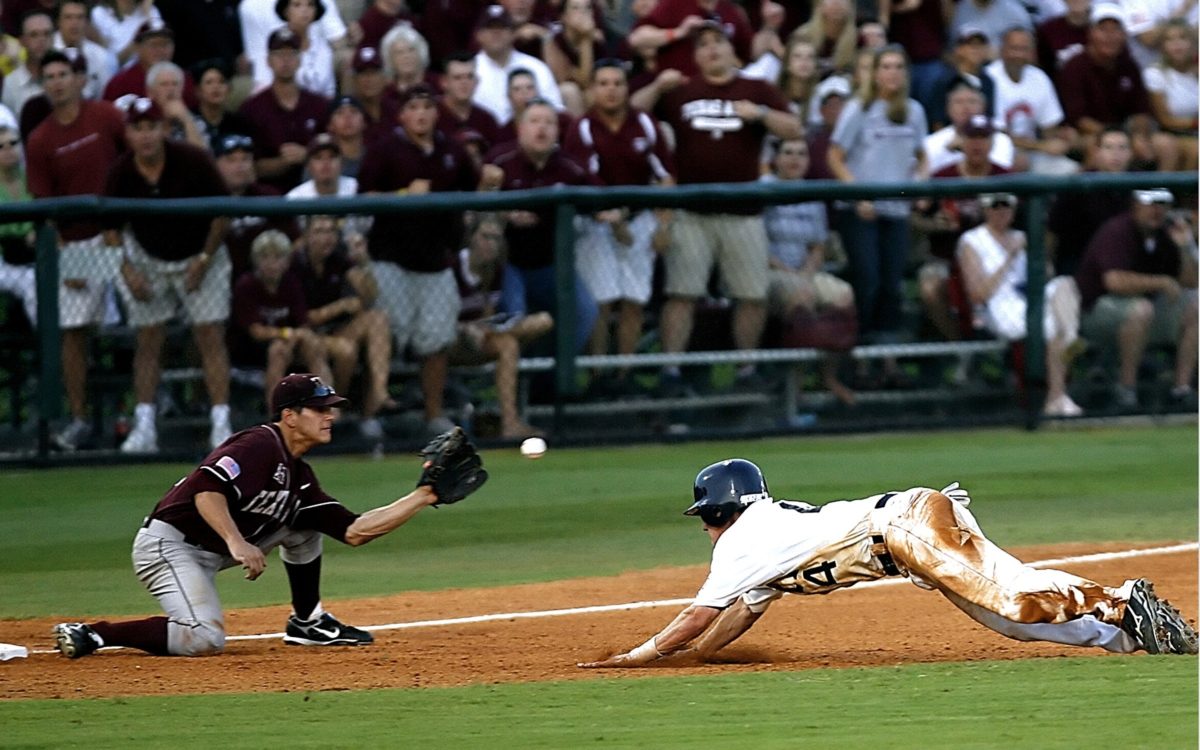 Baseball player sliding into third base and about to be tagged out.