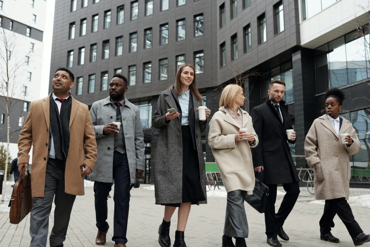 A group of people of different racial backgrounds walking together and dressed professionally.