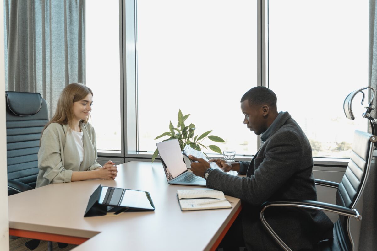 Man sitting behind desk apparently interviewing a young woman.