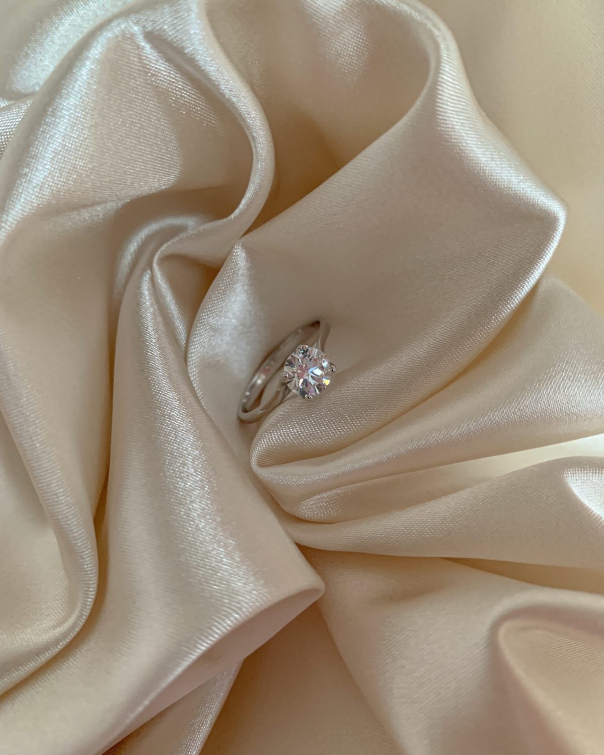 An engagement ring on white silk cloth.