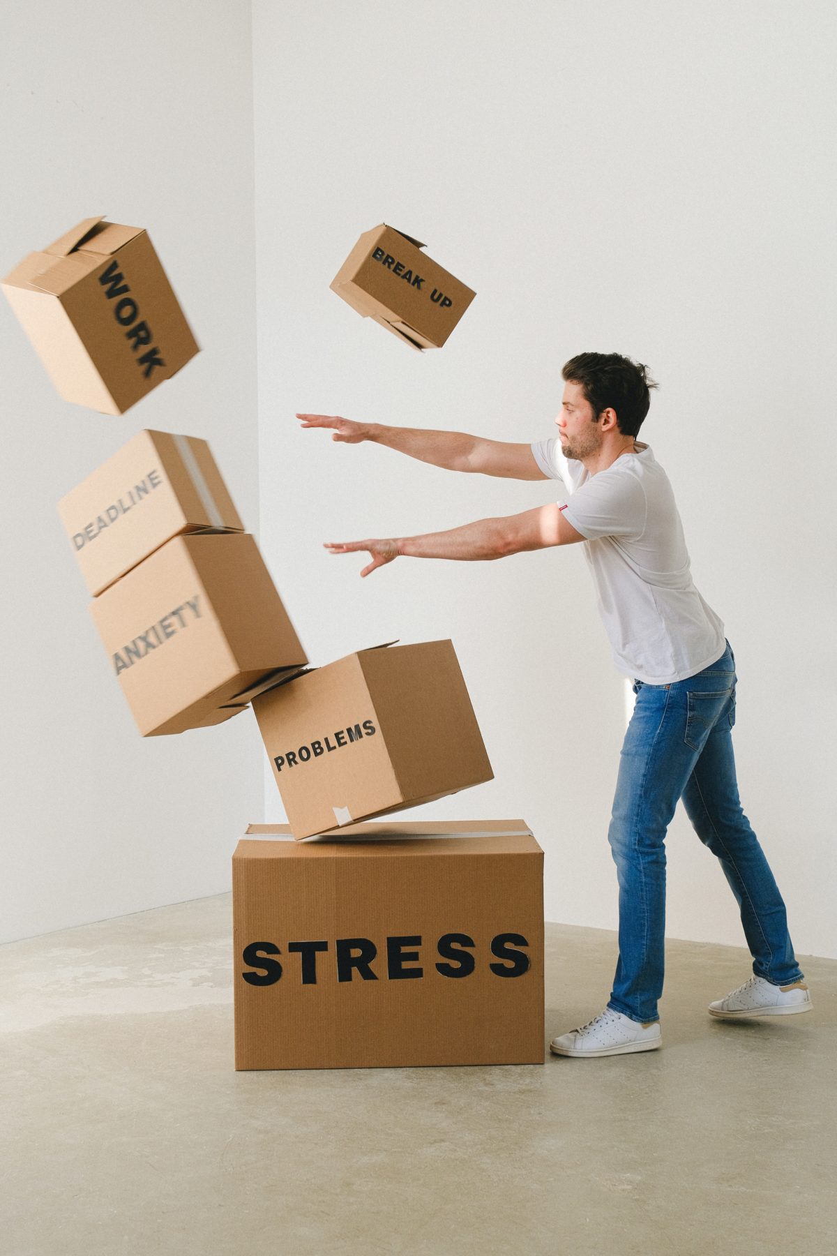 Man toppling boxes labeled "Break up, "Work,," "Deadline," "Anxiety," "Problems," and "Stress."