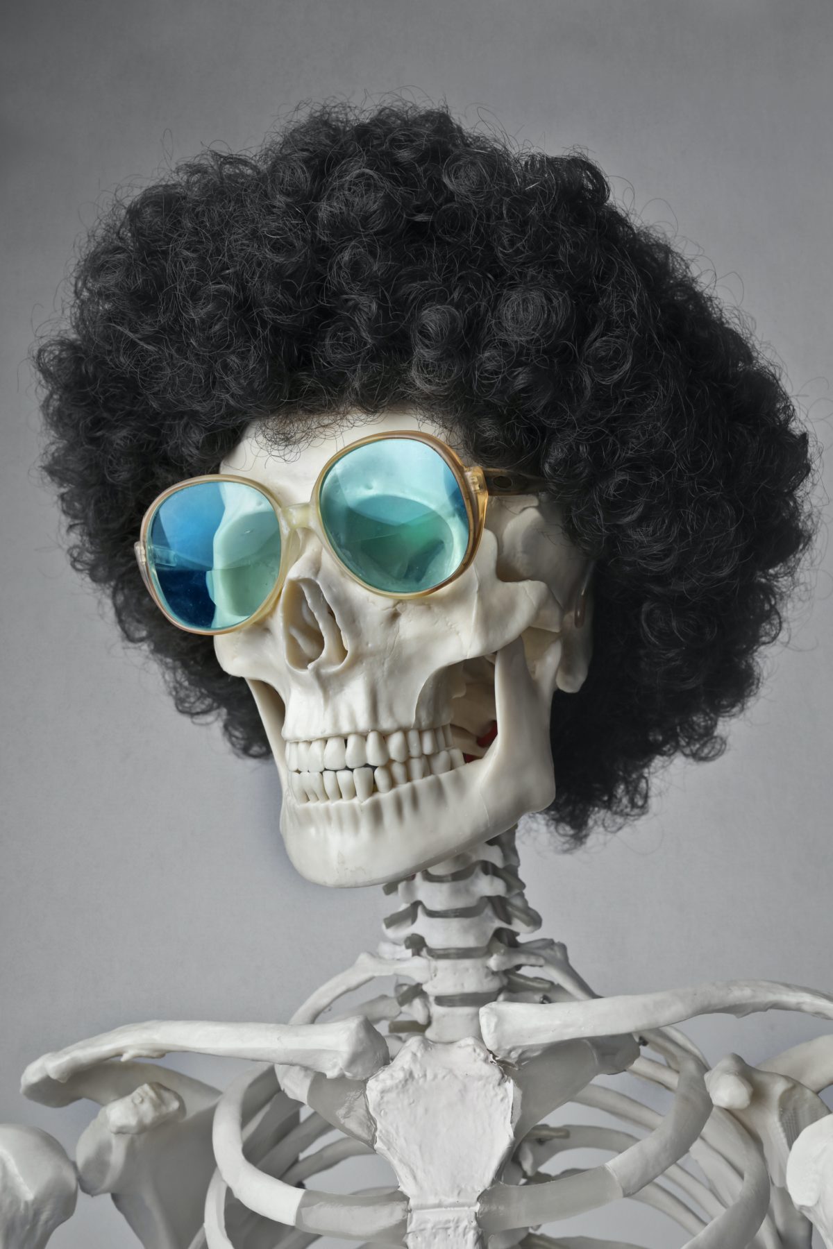 A skeleton wearing a wig and sunglasses.