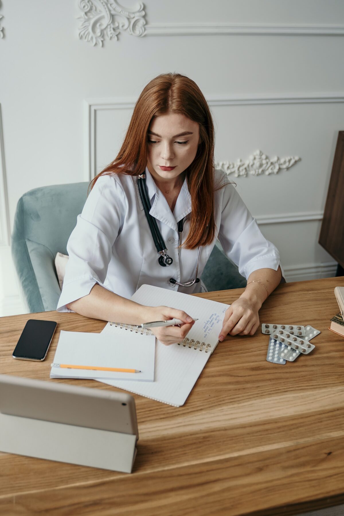 Doctor sitting at her desk writing notes.