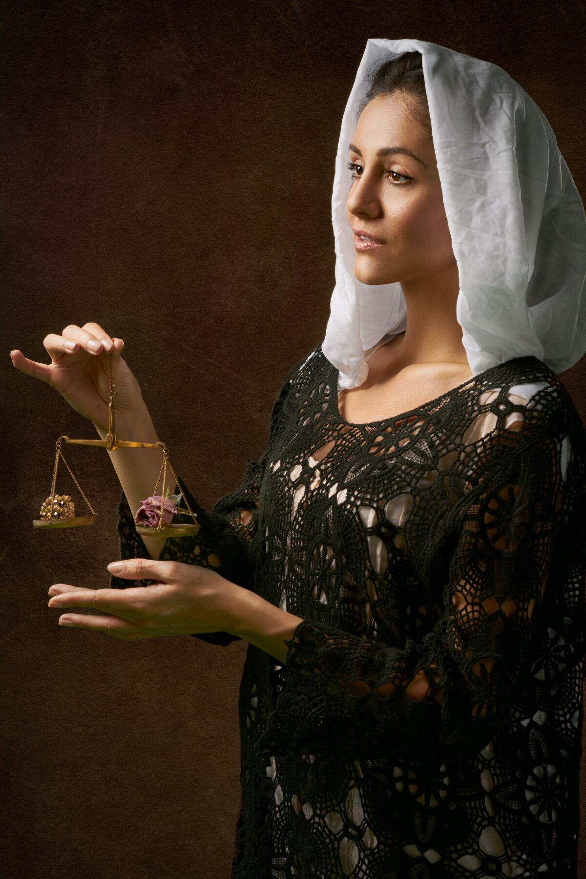 Woman holding a small balance with two different items on it.