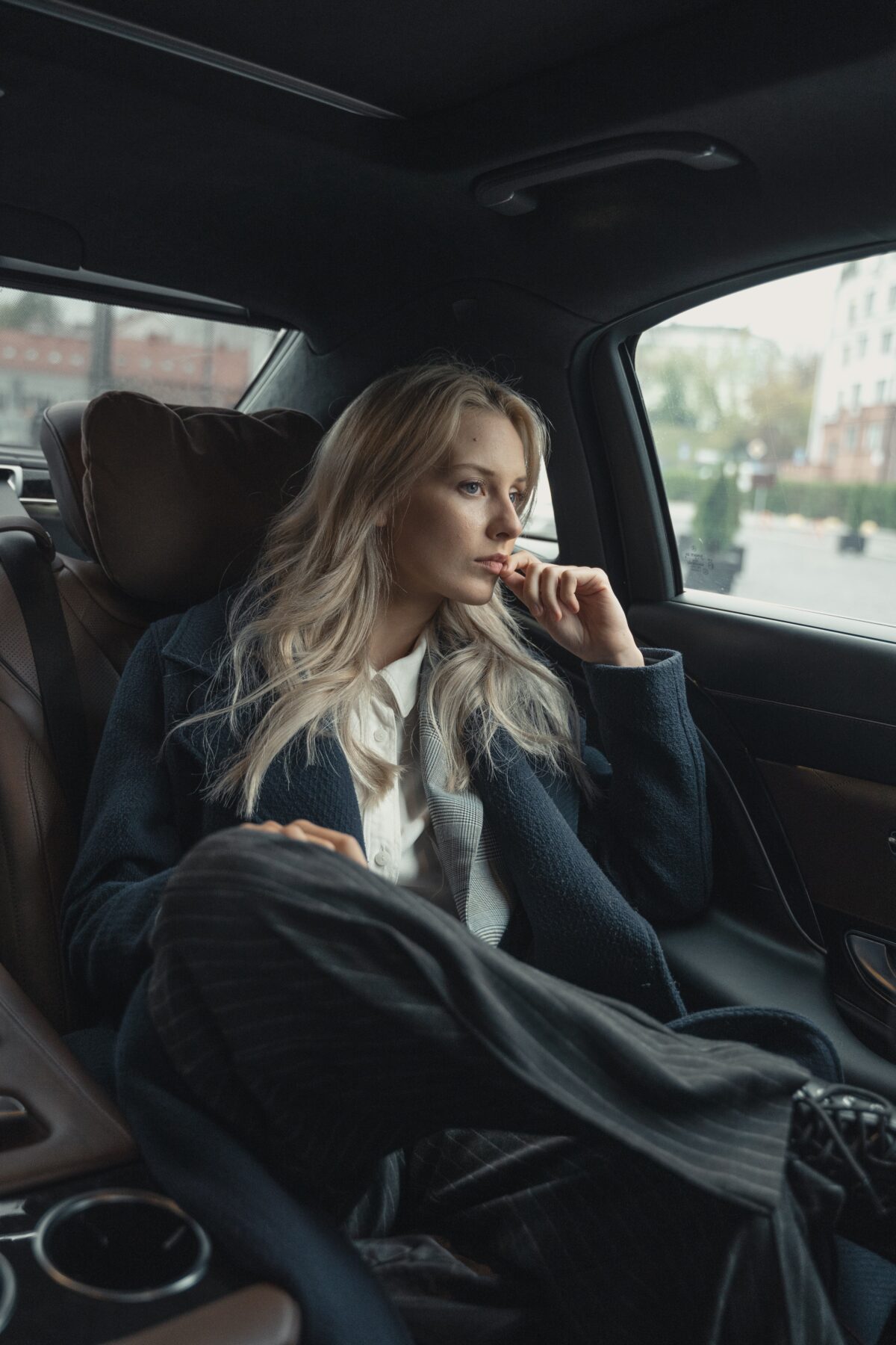 Woman looking pensive in the back seat of a car.