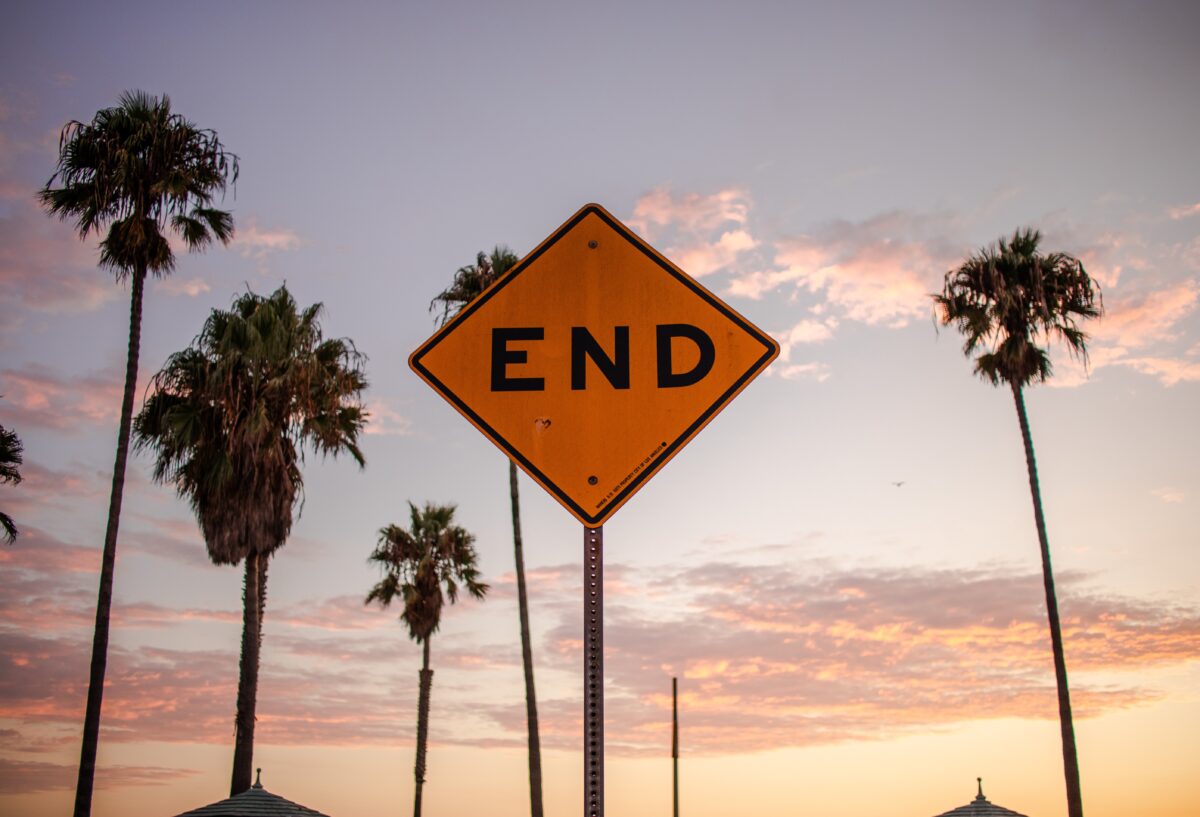 A caution sign with the word "End" against a background of palm trees and an evening sky.