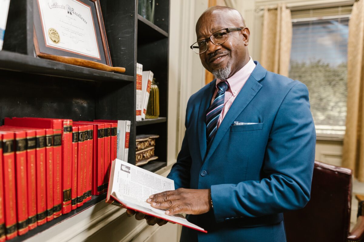 A man holding a book in a library. Looks like a lawyer.