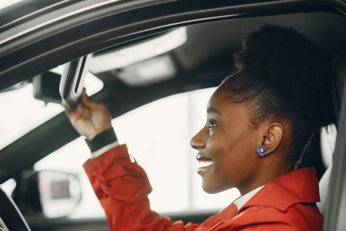 Woman in car looking at mirror on sunvisor.