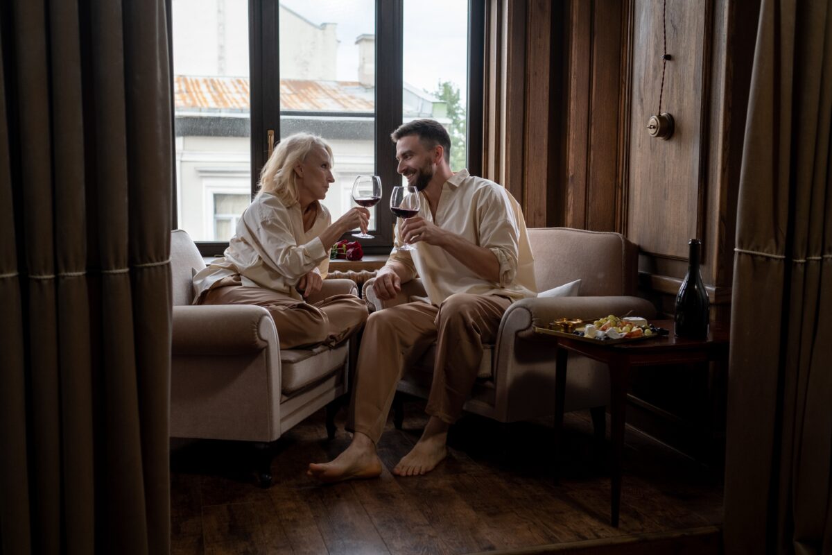 An older woman and younger man sitting together and drinking wine.