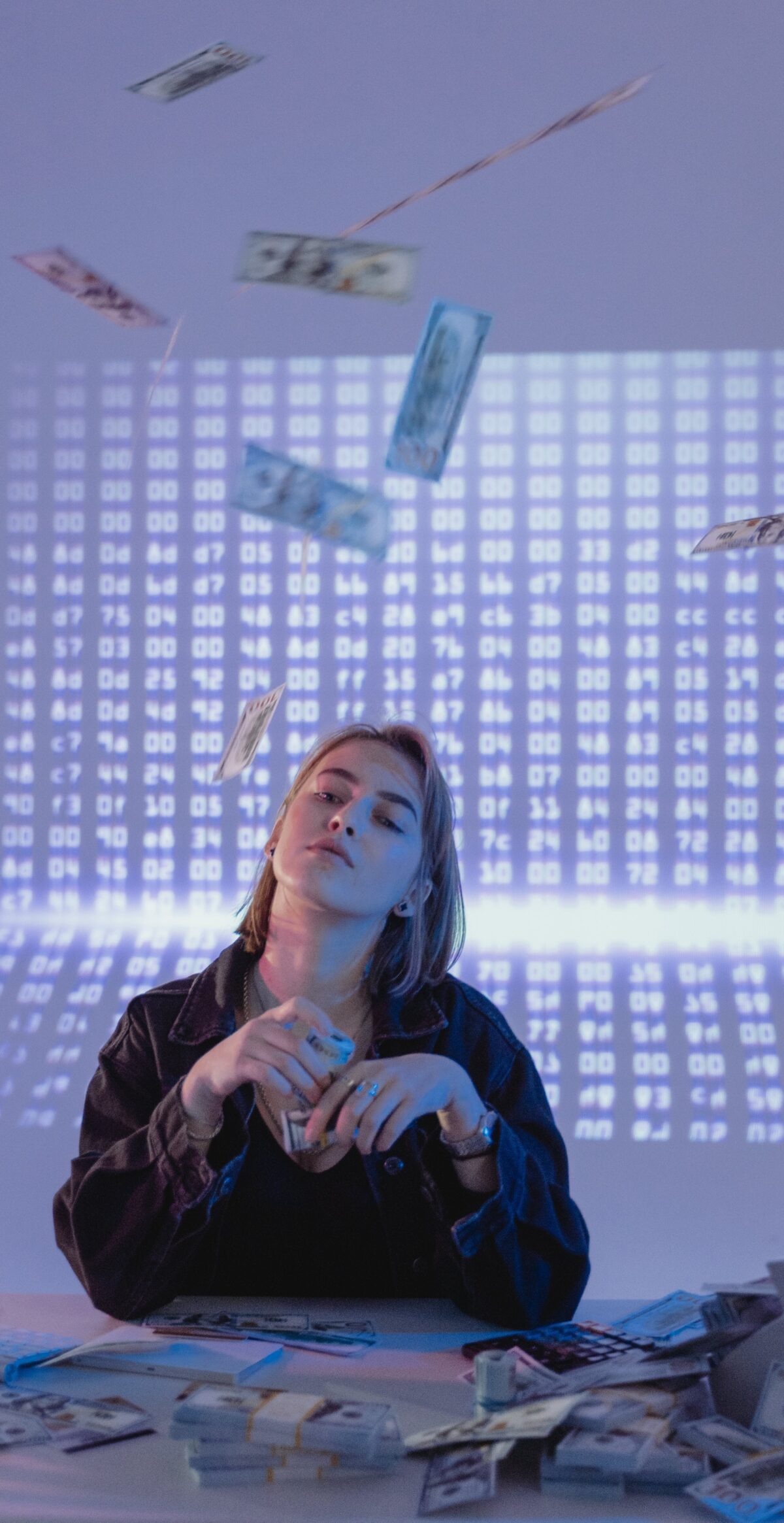 Woman sitting at desk with dollar bills on the desk and in the air.