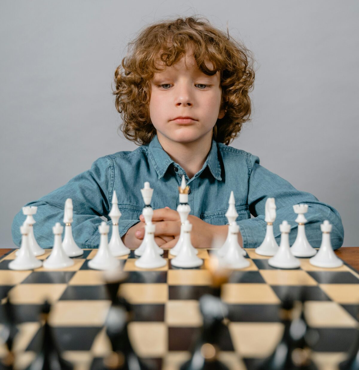 Boy staring at chessboard.