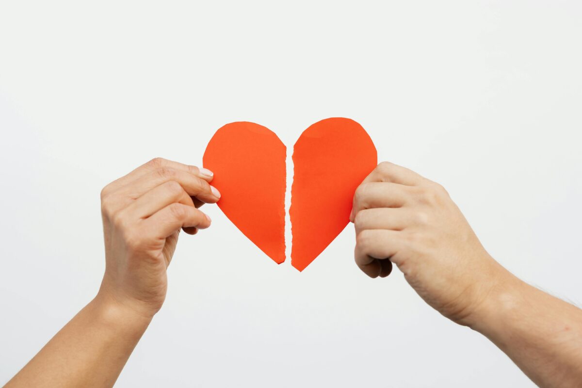 Two hands, each holding half of a broken heart.