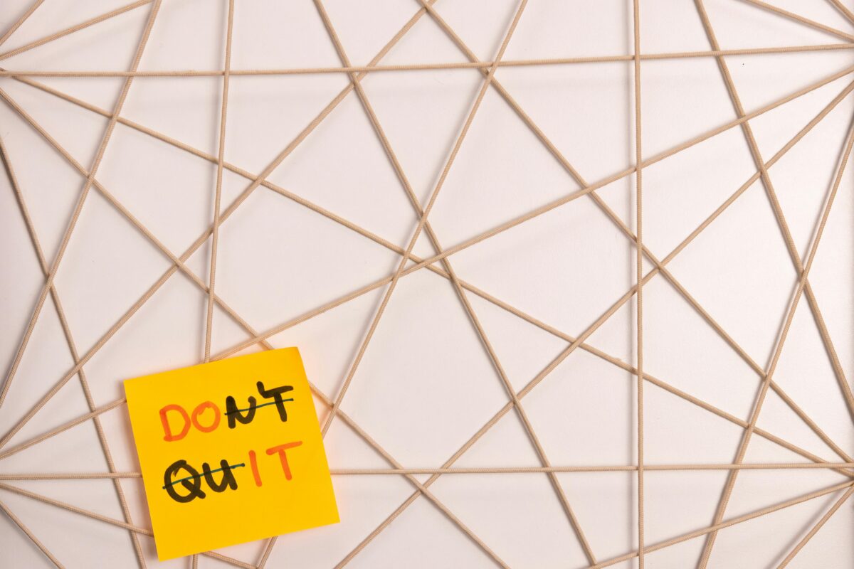 A post-it note that says Don't Quit and Do It at the same time, by crossing out letters.