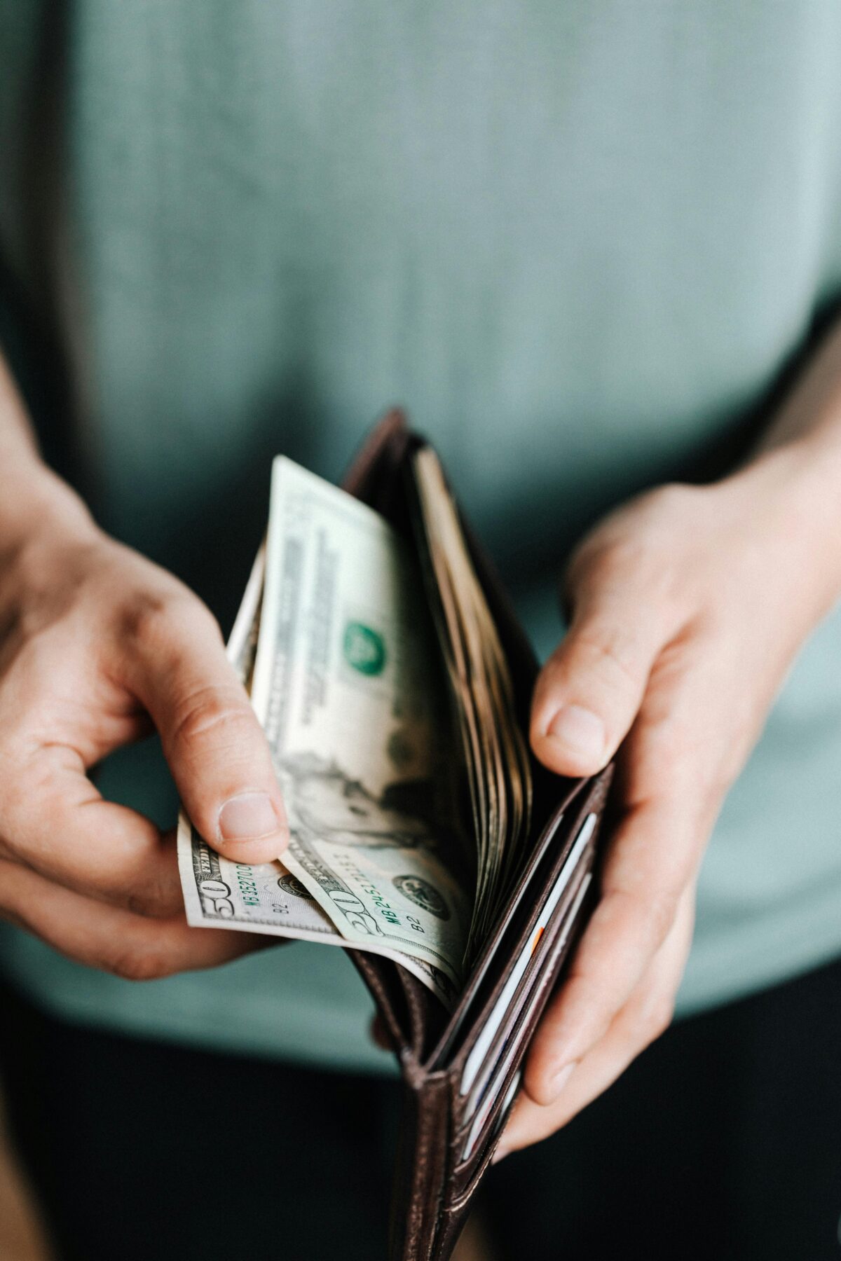 A man opening his wallet and taking money out. Photo by Photo By: Kaboompics at Pexels.