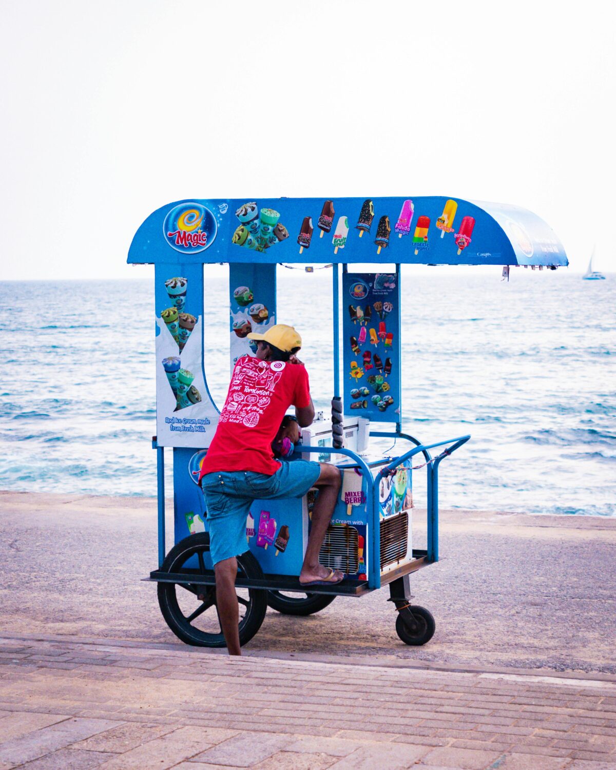 A vendor with an ice cream cart on the beach.