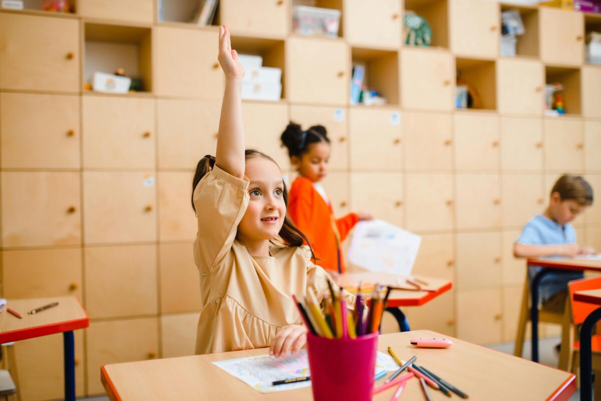 A young girl in class raising her hand to ask a question