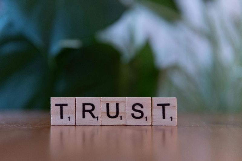 The Word "Trust" spelled out in scrabble tiles.