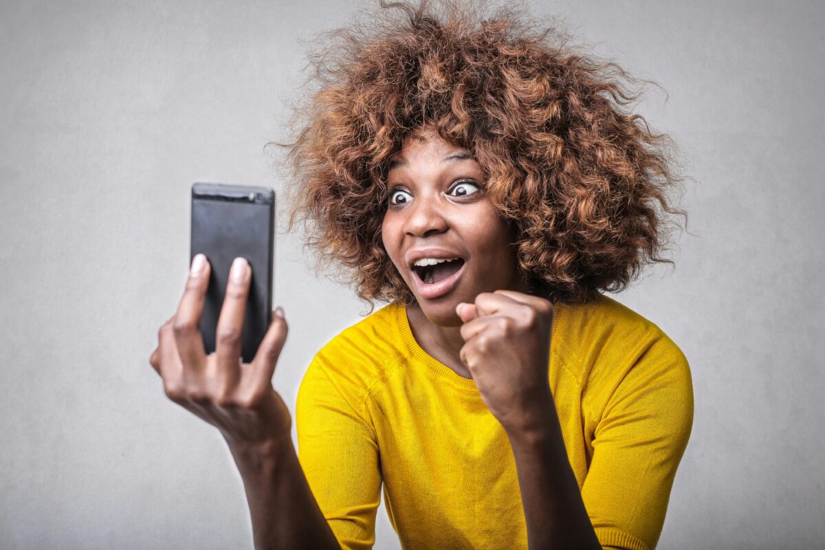 A woman looking at her phone and looking surprised.