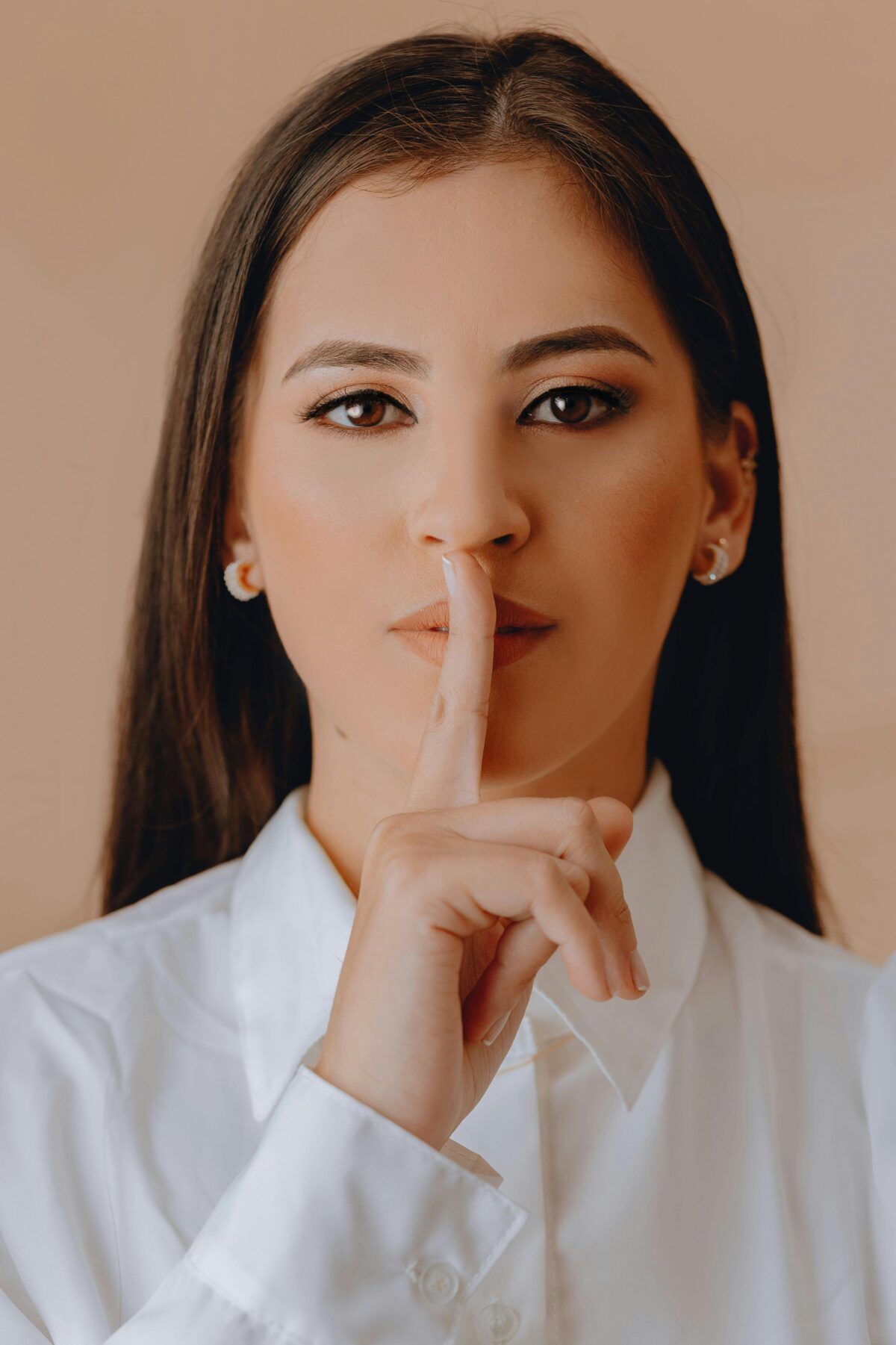 Woman holding finger to mouth indicating do not speak.