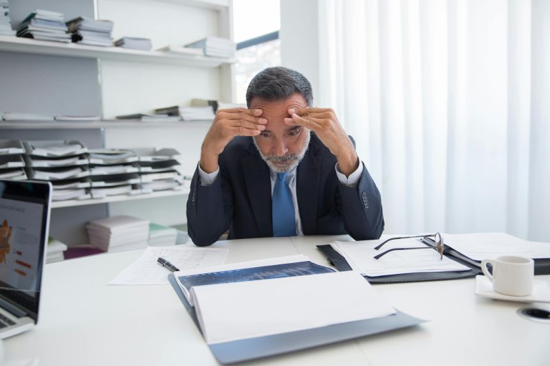 Man at desk looking stressed.