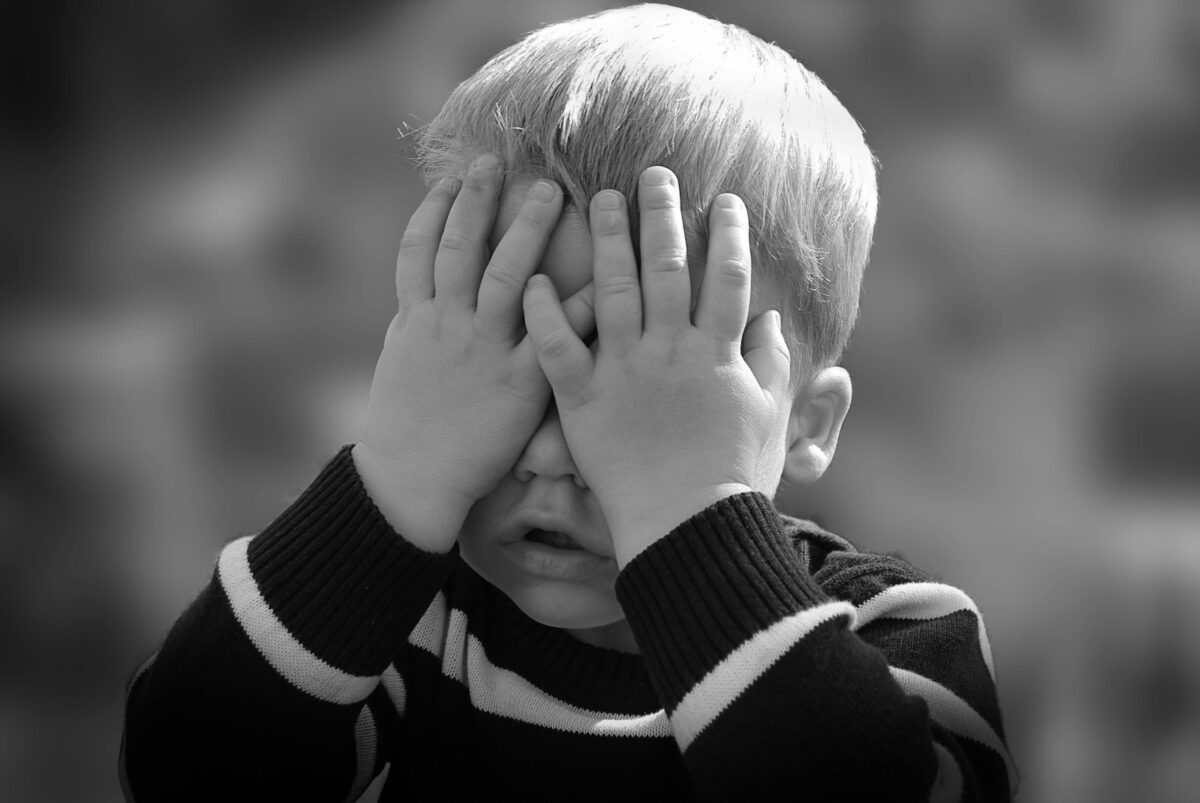A small child covering his eyes.