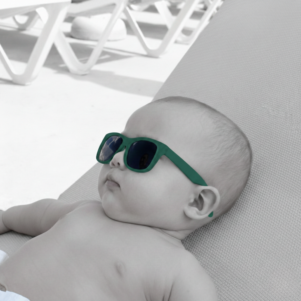 Baby lying on a lounge chair wearing sunglasses.