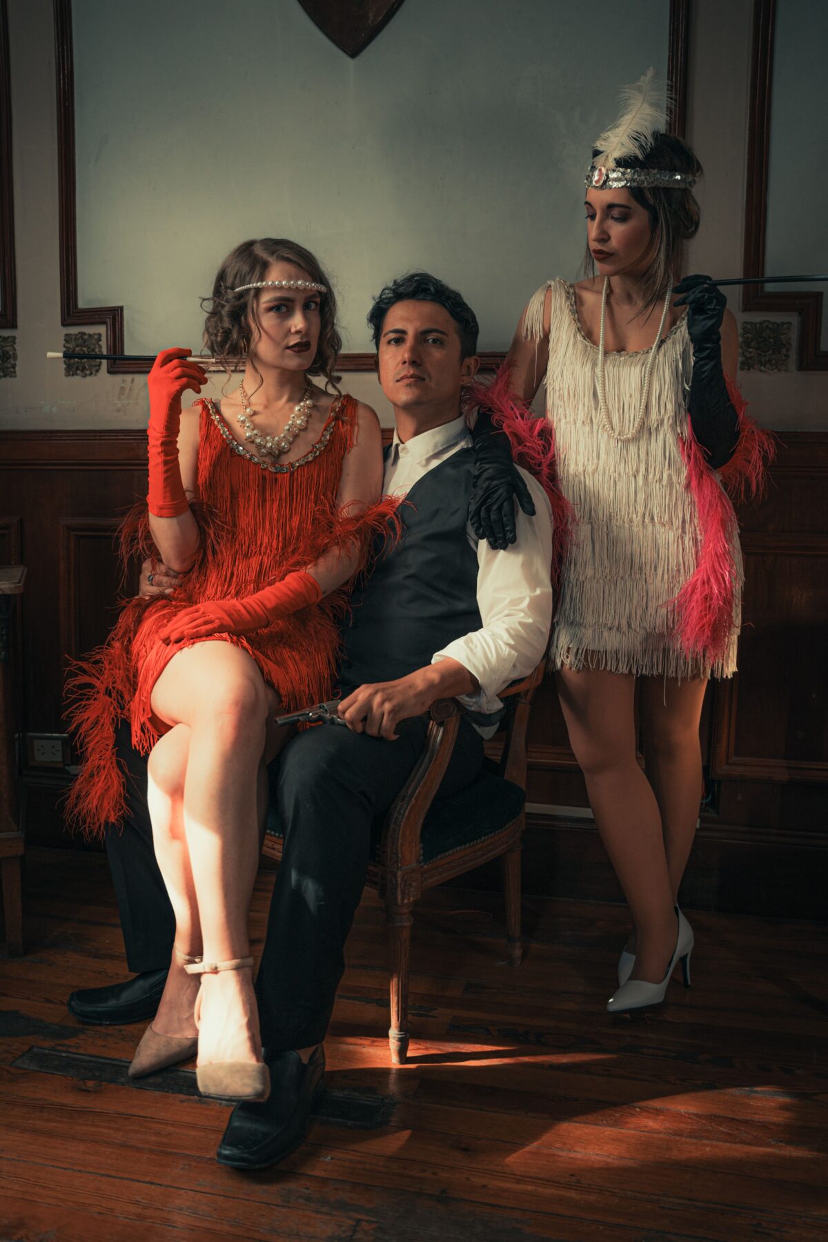 A man and two women posing for a picture dressed in 1920's fashion.