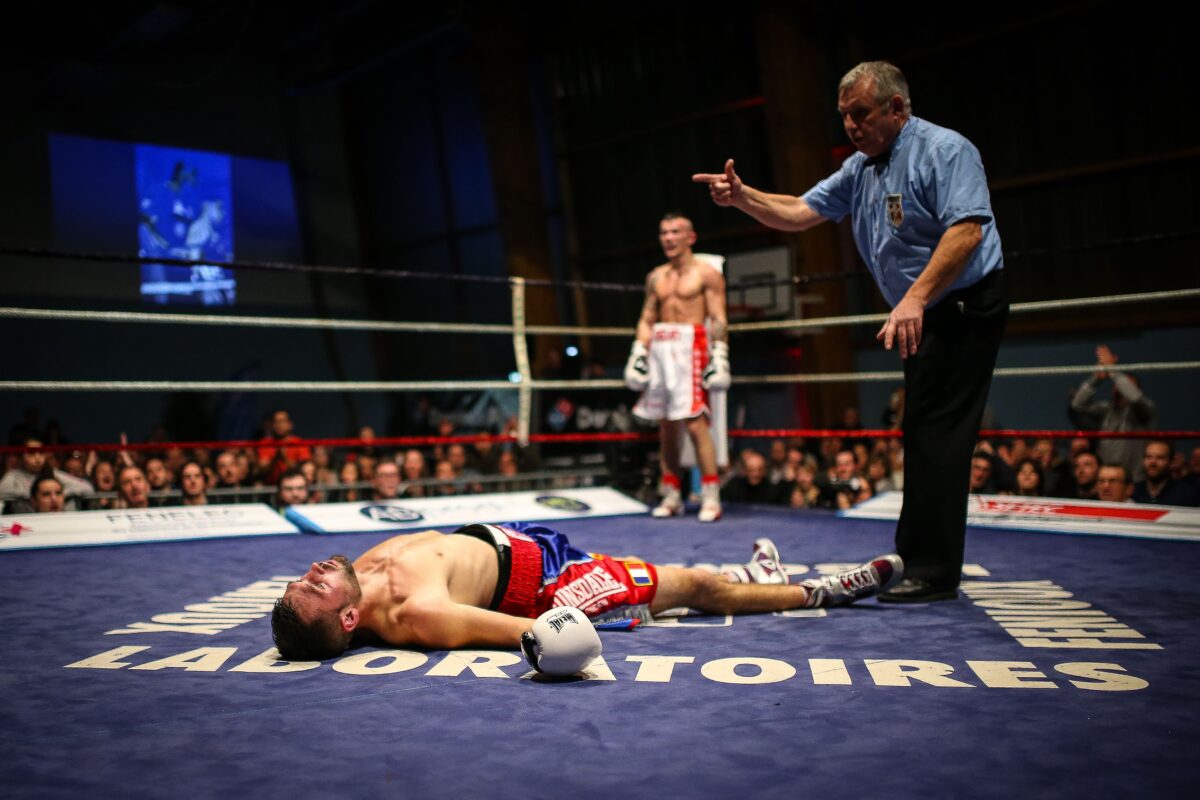 Boxing match with one fighter out for the count and the referee and other fighter watching.
