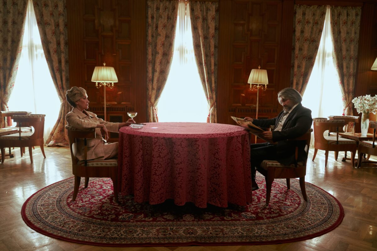 A wealthy couple sitting at a table in an ornate dining room.