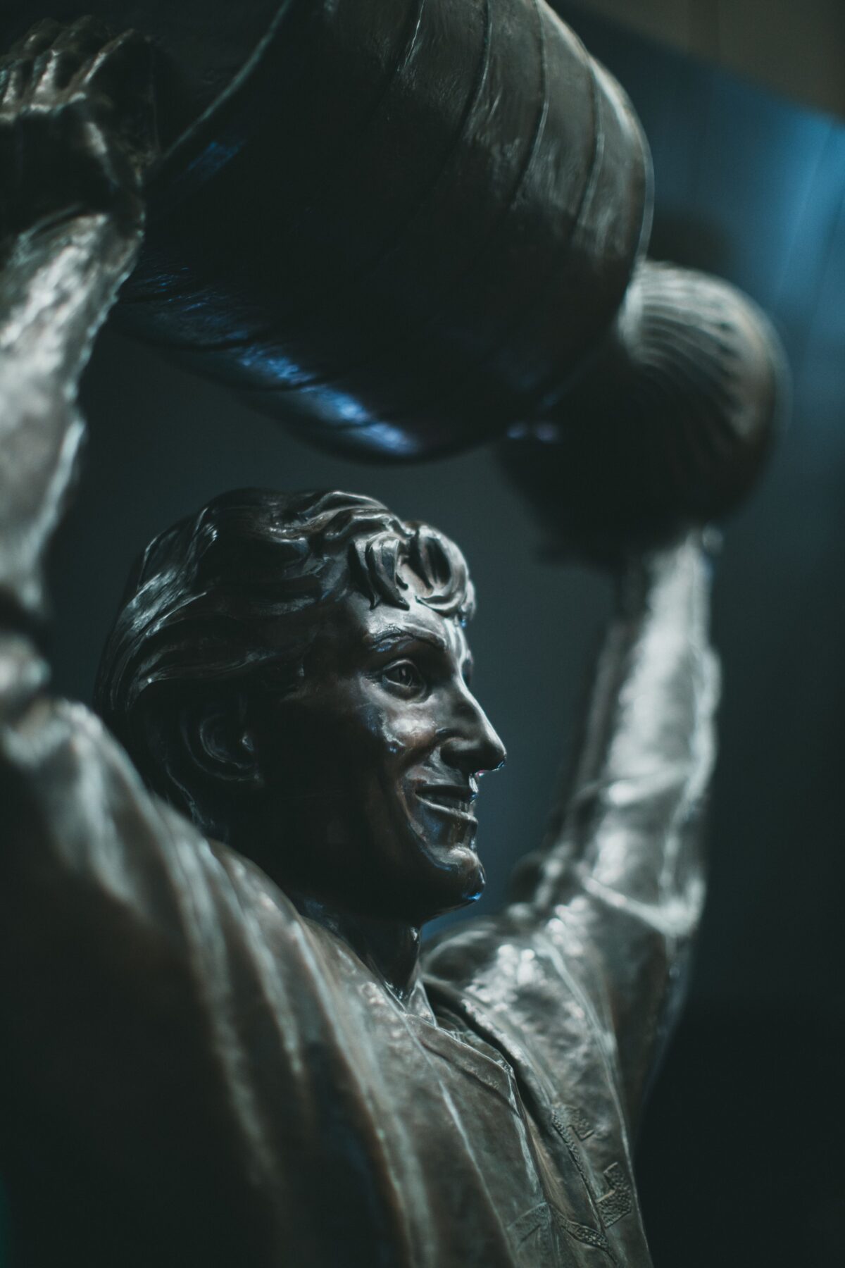A bronze statue of a hockey player holding the Stanley Cup over his head.