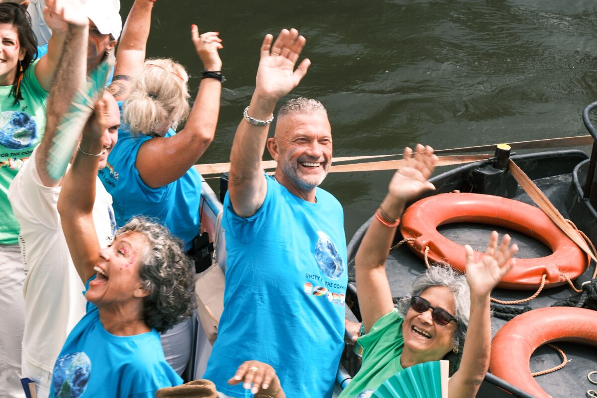 Men and women waving goodbye from a small boat.